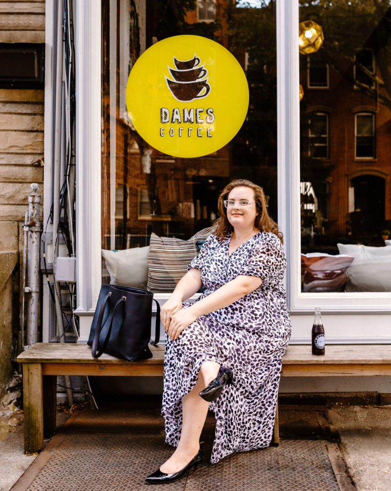 Jenna VanLeeuwen sitting on a bench in front of a coffee shop